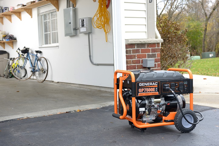 A portable generac generator outside of a home's garage.